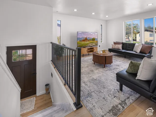 Open-concept living area featuring wood-finish flooring, recessed lighting, and large windows