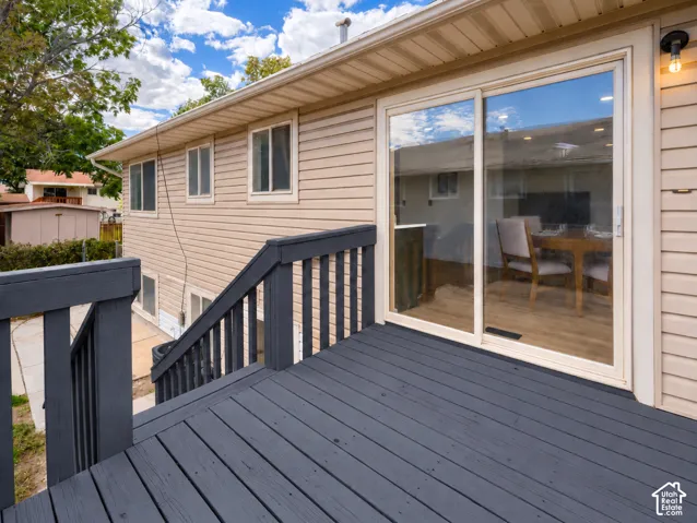Sliding glass door access to an exterior deck with railing and stairs, featuring horizontal siding