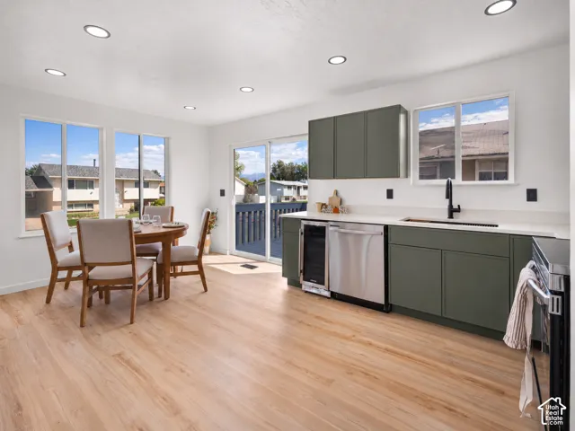 Recessed lighting, wood-finish flooring, white walls, green cabinetry, and a sliding glass door to an outdoor area