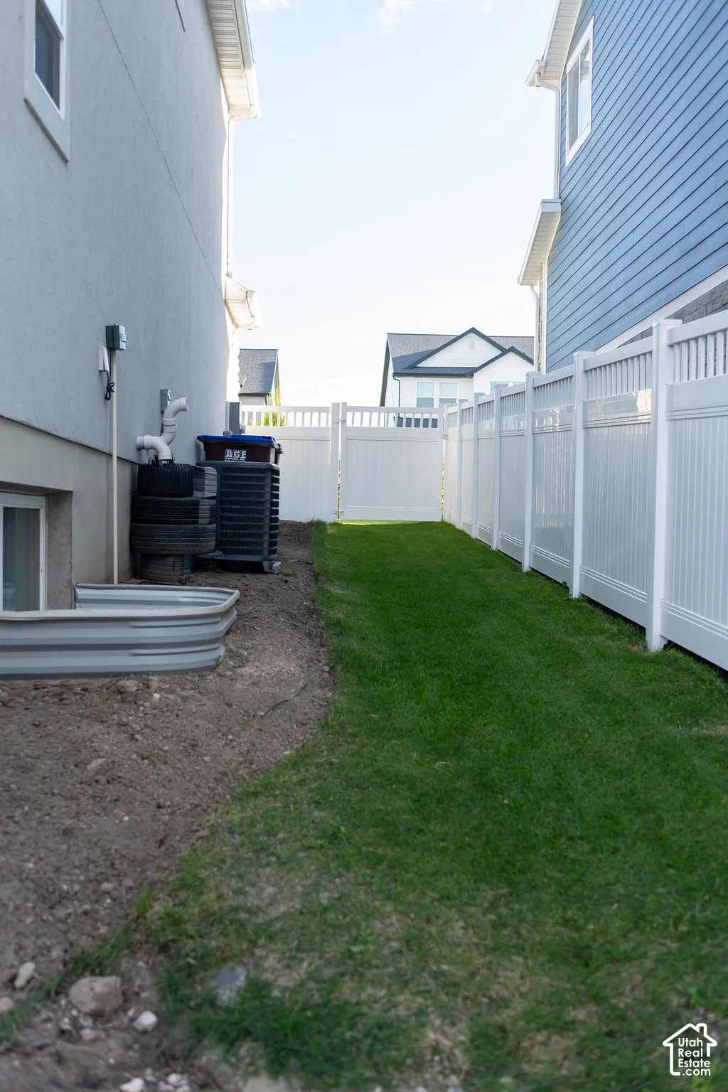 Expansive side yard featuring a manicured lawn, full privacy fencing, and an accessible window well