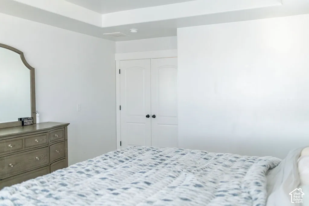 Tray ceiling featuring recessed lighting, white walls, and white bi-fold closet doors