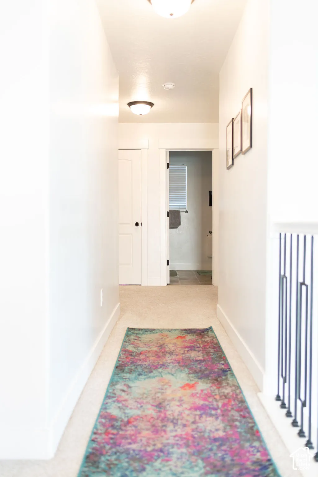 Carpeted hallway with white walls and overhead flush-mount lighting