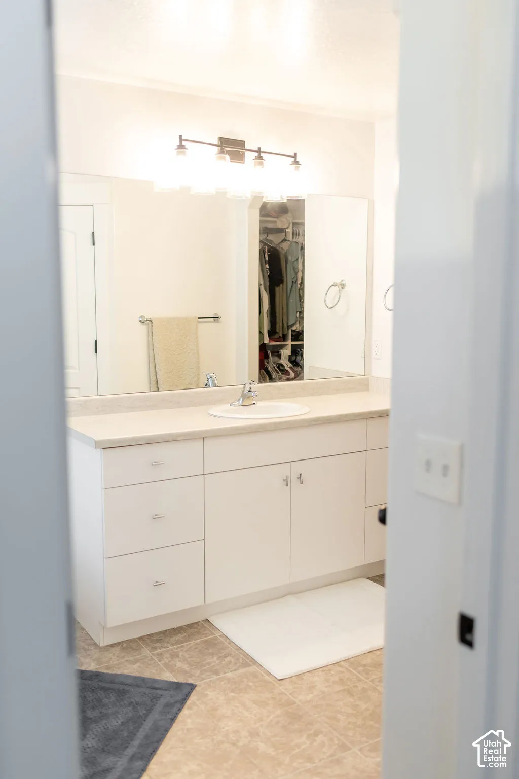 White vanity with a single sink and light countertop