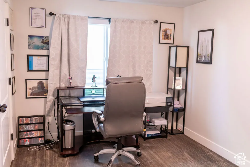 Wood-finish flooring with white baseboards, a window with curtains, and a white door with dark hardware