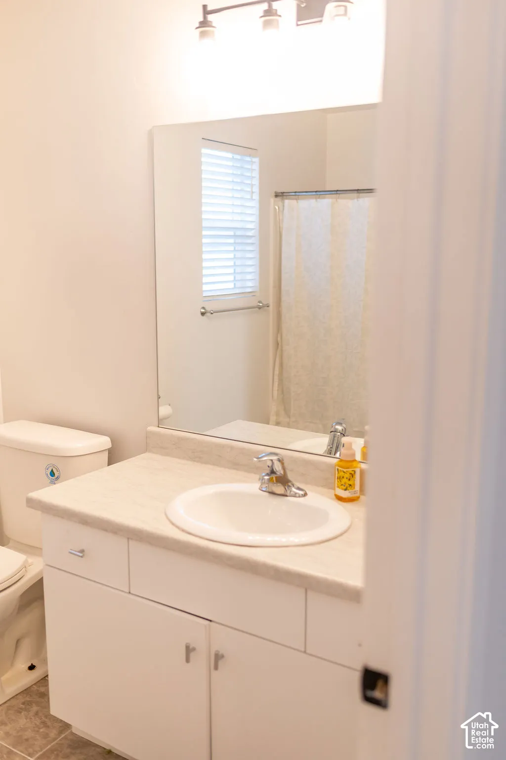 White vanity with a laminate countertop, integrated sink, and chrome faucet
