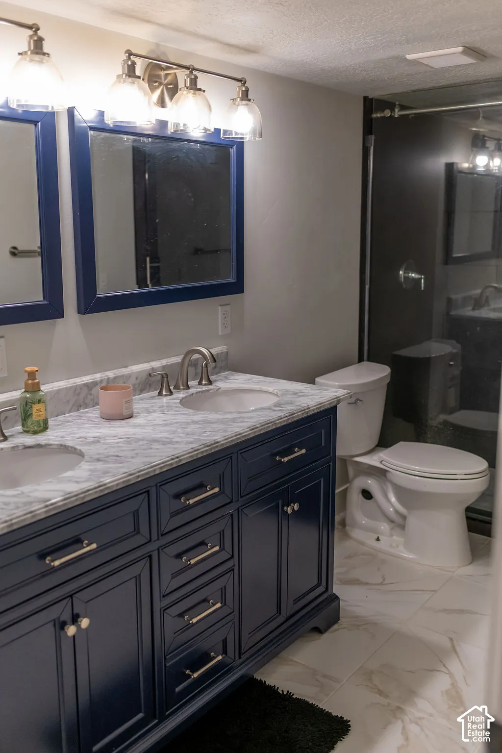 Dual-sink vanity with a light-toned countertop, dark-toned cabinetry, and satin nickel hardware