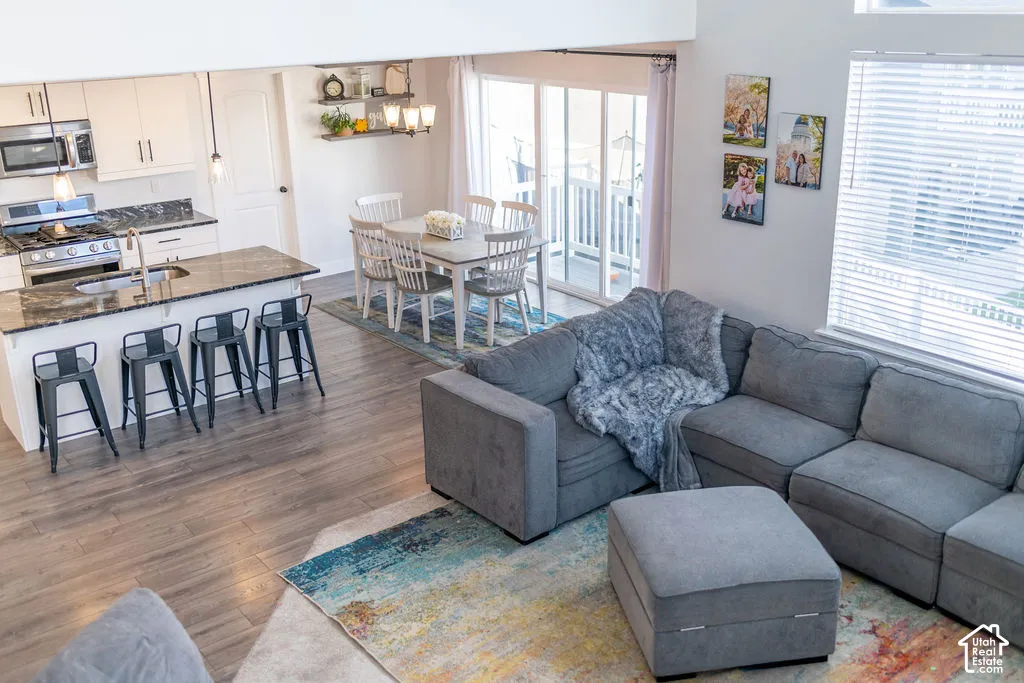 White cabinetry with dark countertops, stainless steel appliances, wood-finish flooring, dining area, and sliding glass door
