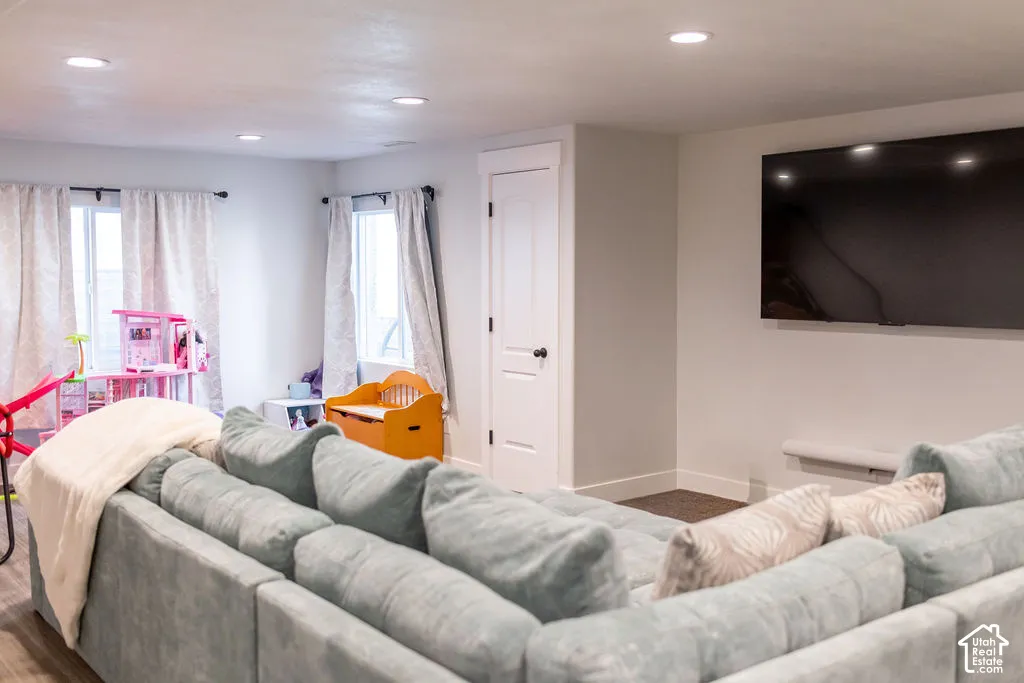 Recessed lighting illuminates this space, featuring light-toned walls and wood-finish flooring