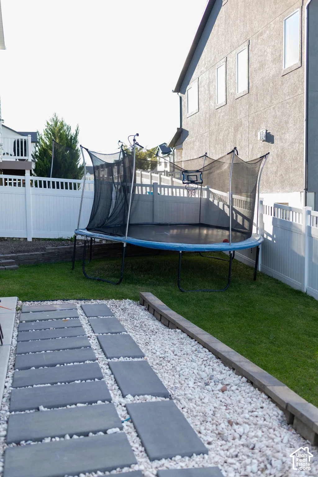 Manicured lawn with white picket fencing, concrete paver pathway, and decorative white gravel