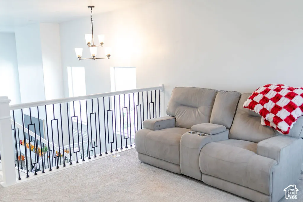 Loft area featuring a contemporary chandelier, white walls, and light-colored carpeting