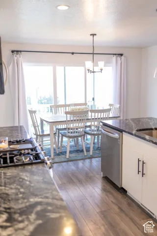 Kitchen featuring dark stone countertops, built-in gas range, stainless steel dishwasher, and white cabinetry with matte black hardware