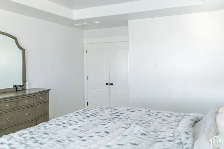 Tray ceiling featuring recessed lighting, white walls, and white bi-fold closet doors