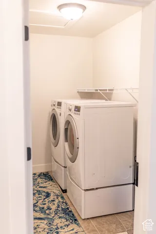 Laundry room featuring light-toned tile flooring, built-in wire shelving, and a flush mount ceiling light