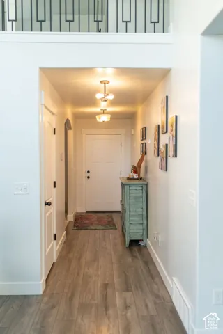 Hallway featuring wood-finish flooring, recessed lighting, white trim, and a contemporary black metal railing