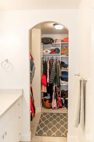 Archway entry to a walk-in closet featuring built-in shelving, clothing rods, and an overhead light fixture