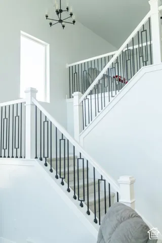 Split-level staircase featuring carpeted treads, white newel posts, and decorative black metal balusters