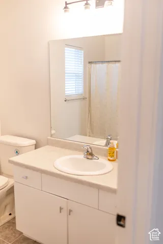 White vanity with a laminate countertop, integrated sink, and chrome faucet