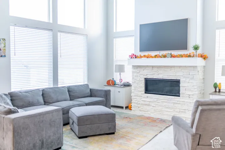 Floor-to-ceiling windows with integrated blinds, a stone-clad fireplace, and neutral wall tones