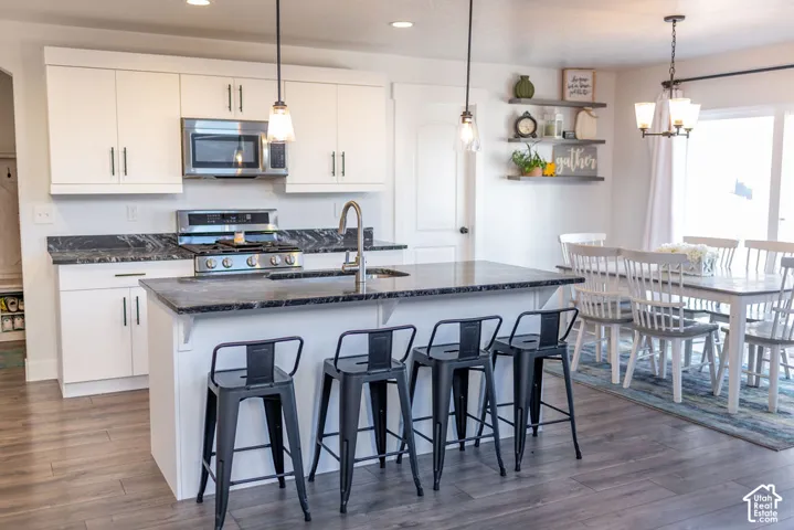 Kitchen featuring wood-finish flooring, white cabinetry, dark countertops, and stainless steel appliances