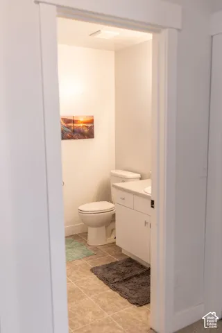 Functional bathroom featuring ceramic tile flooring, a standard toilet, and a vanity sink with integrated storage