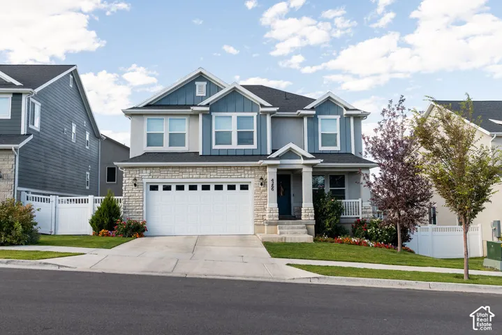 Two-story residence featuring a stone and siding exterior, two-car garage, and a covered front porch with columns