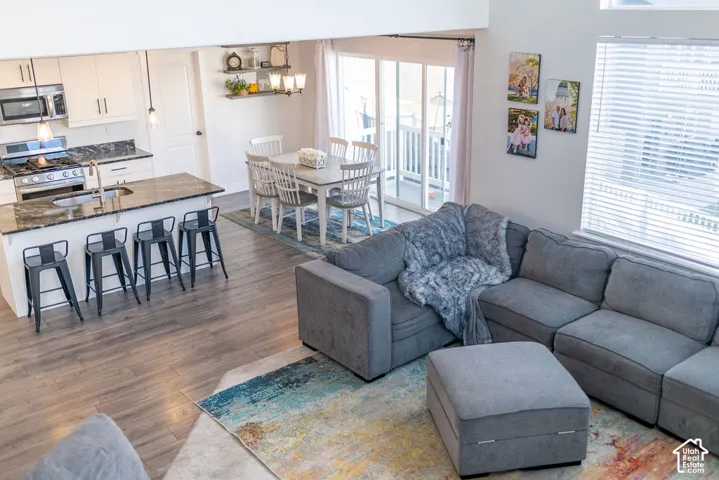 White cabinetry with dark countertops, stainless steel appliances, wood-finish flooring, dining area, and sliding glass door