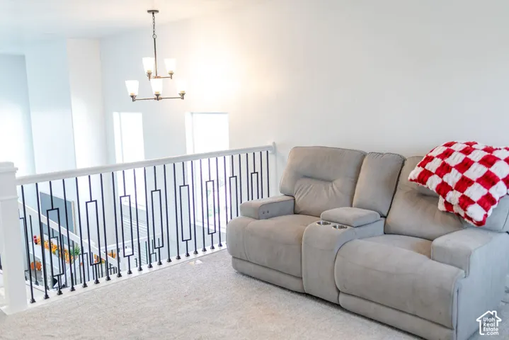 Loft area featuring a contemporary chandelier, white walls, and light-colored carpeting