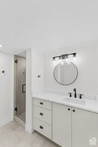 White vanity with a solid surface countertop, undermount sink, and matte black fixtures