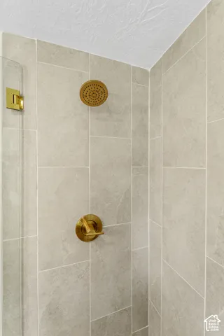 Shower with light gray tile surround, brass finish rainfall showerhead, and brass finish single-handle control