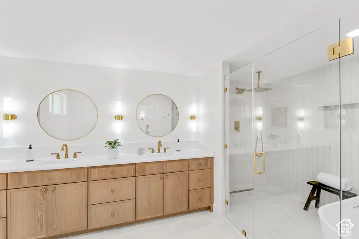 Dual vanity with wood-finish cabinetry, white countertops, and gold-tone fixtures