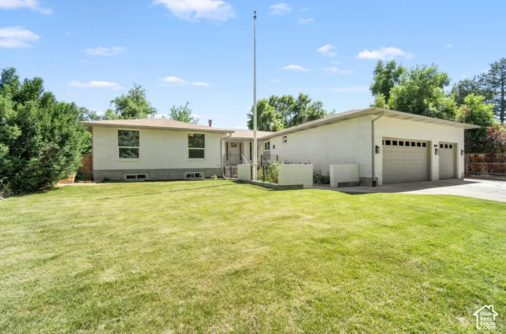Spacious single-story residence on expansive grounds featuring a manicured lawn, mature landscaping, and detached three-car garage