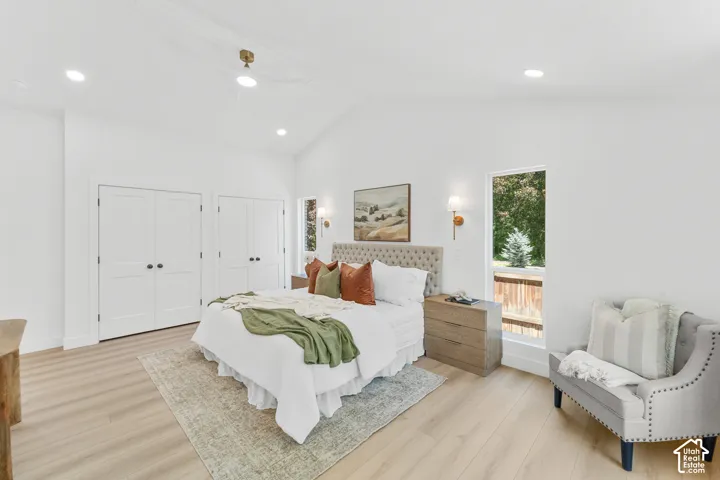 Vaulted ceiling with a ceiling fan, light wood-finish flooring, recessed lighting, and white paneled closet doors