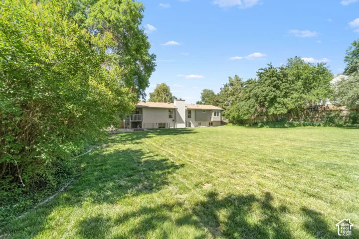 Expansive grassy yard with mature perimeter trees and a multi-level deck