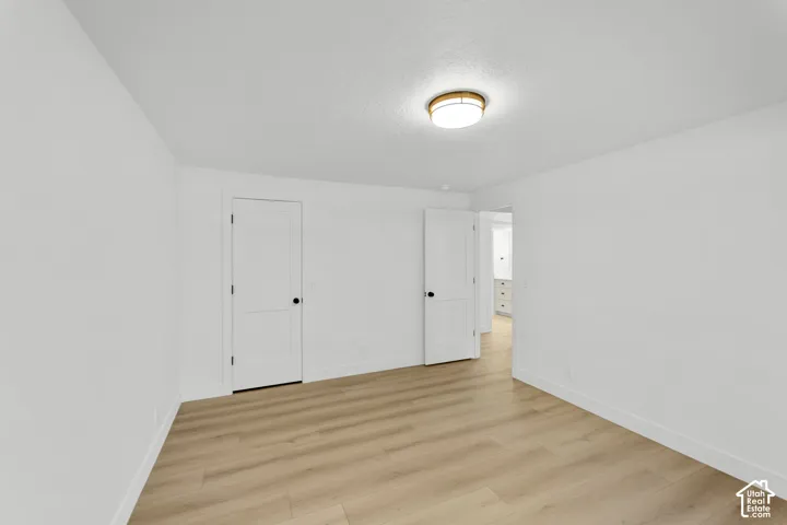 Recessed ceiling light fixture, wood-finish flooring, white painted walls, white two-panel interior doors, and black door hardware