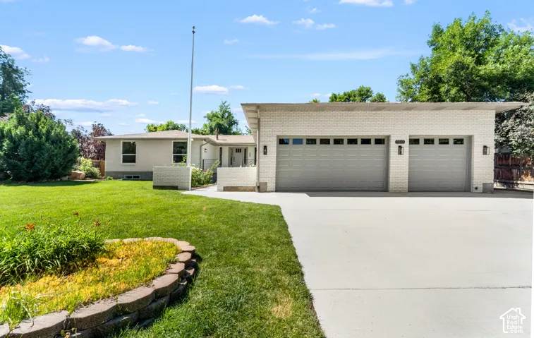 Expansive concrete driveway, two-car garage with panel doors, and exterior brick finish