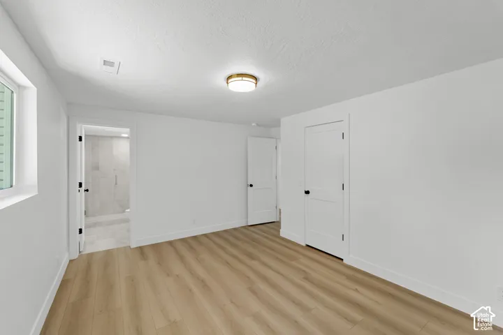 Light wood-finish flooring, white walls, and a window with natural light