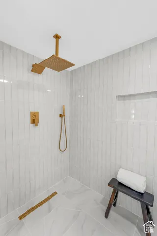 Vertical subway tile shower surround with a built-in niche, ceiling-mounted rain shower head, and a linear floor drain