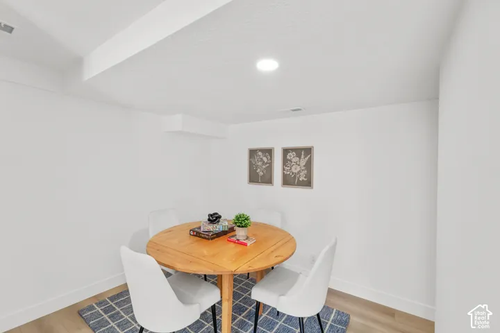 Recessed ceiling lighting, smooth white walls, white trim, and wood-finish flooring