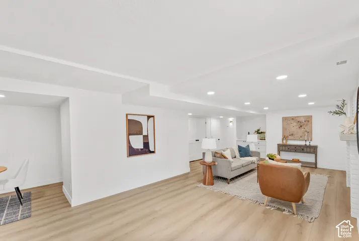 Recessed lighting illuminates the open living area featuring wood-finish flooring and white walls