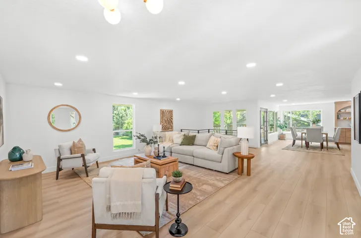 Expansive living area with light wood-finish flooring, numerous recessed lights, large windows, and a built-in dining area cabinet