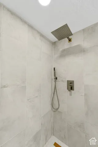Shower with light-toned rectangular tile walls, a square rainfall showerhead, and a handheld shower wand