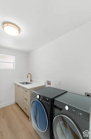 Wood-finish flooring with a light-colored vanity, undermount sink, and brass-finish faucet