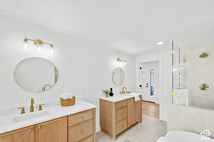 Dual wood-finish vanities with white countertops, brass fixtures, and circular mirrors