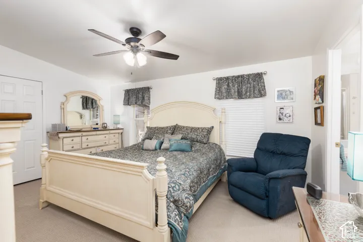 Carpeted bedroom featuring a ceiling fan with light fixture, window with blinds, and white paneled door