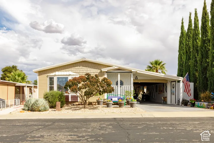 Exterior featuring horizontal siding with shingle accents, a bay window, a covered carport, and mature landscaping