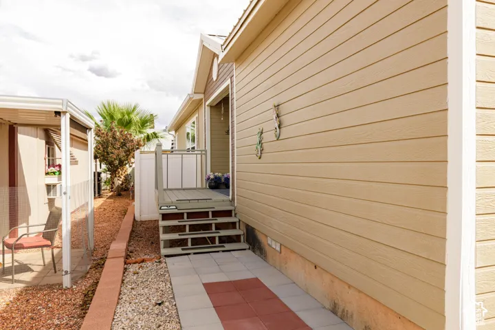 Exterior siding in a neutral tone, elevated deck with railings, and a paver pathway
