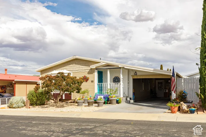 Property exterior featuring a covered front porch, carport, and xeriscaped front yard with mature plantings