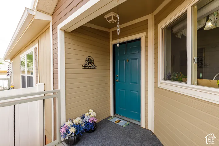 Entryway featuring a paneled teal door, horizontal siding, and a window with white trim