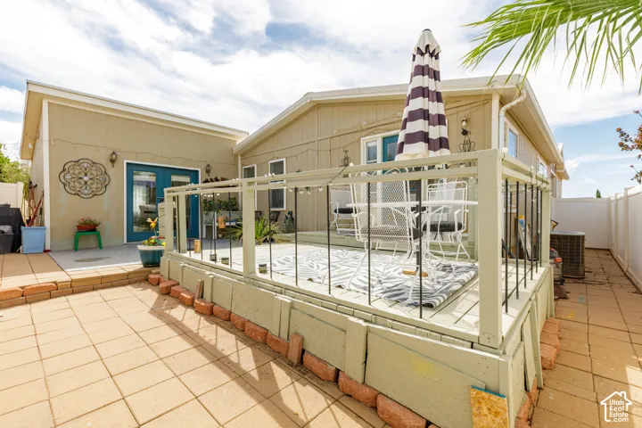 Outdoor patio featuring paver stones, an elevated wood deck with railing, and a privacy fence