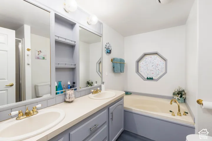 Dual basin vanity with integrated storage, a built-in soaking tub, and an octagonal window
